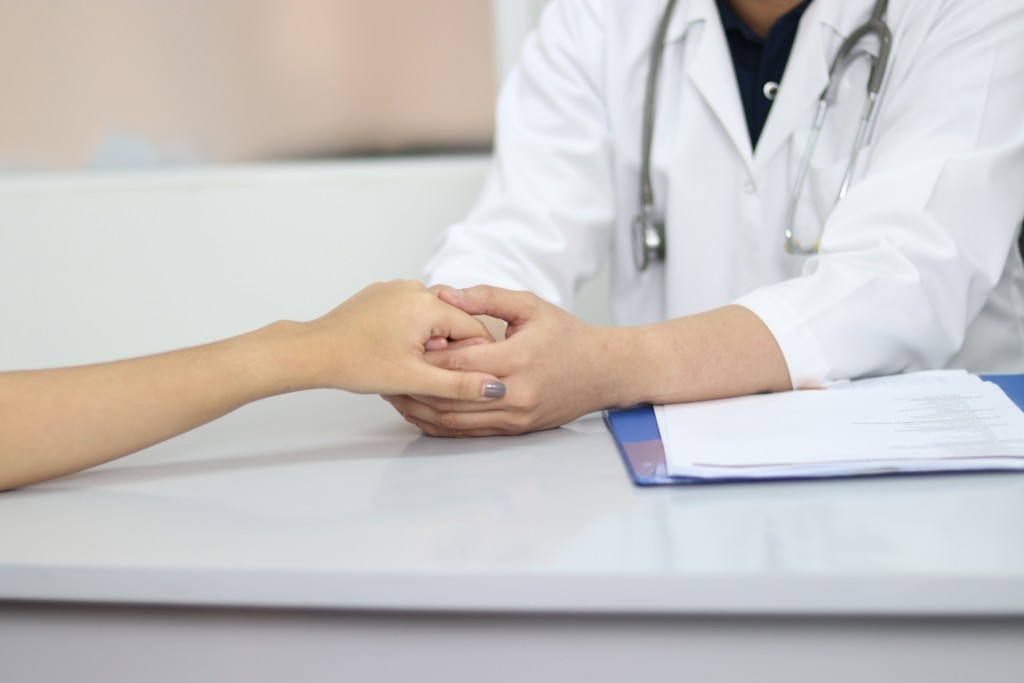 Doctor holds hands with patient